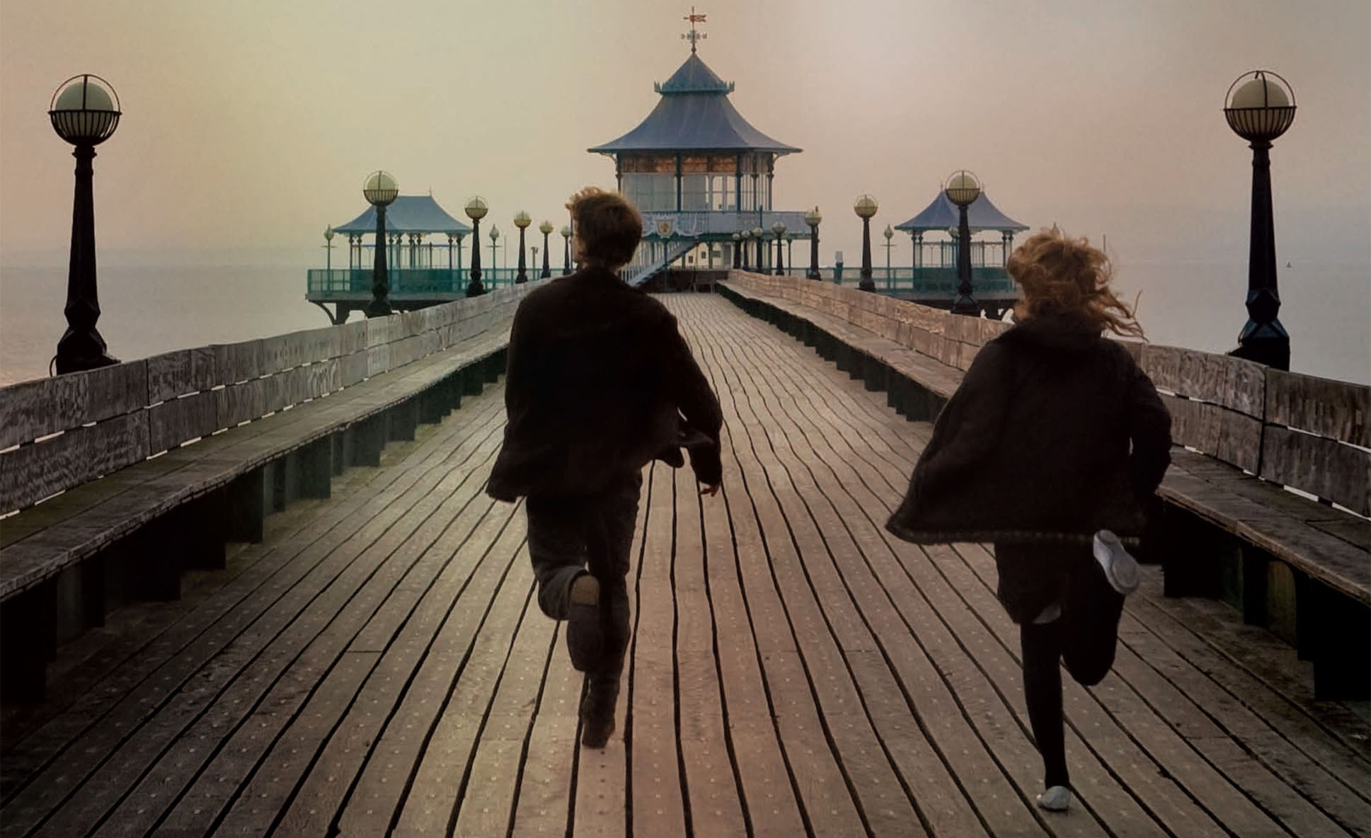 Tommy and Kathy running down a boardwalk - from the movie adaption of 'Never Let Me Go'