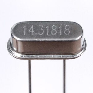 An rectangular metal package with rounded ends, with two metal connecting pins coming out of the bottom. The top is embossed with the number 14.31818. This is a 14.31818 MHz crystal resonator.