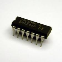 A picture of an integrated circuit. The main body is black with faint grey writing on it that says the part number and the manufacturer. Sticking out on each side are silver metal spikes or legs (this one has 7 on each side). These point downwards, and can be plugged into the grid of holes in our protoboards. One end of the chip has a small semicircle cut out to help figure out which end is which (we call this end the “top”).