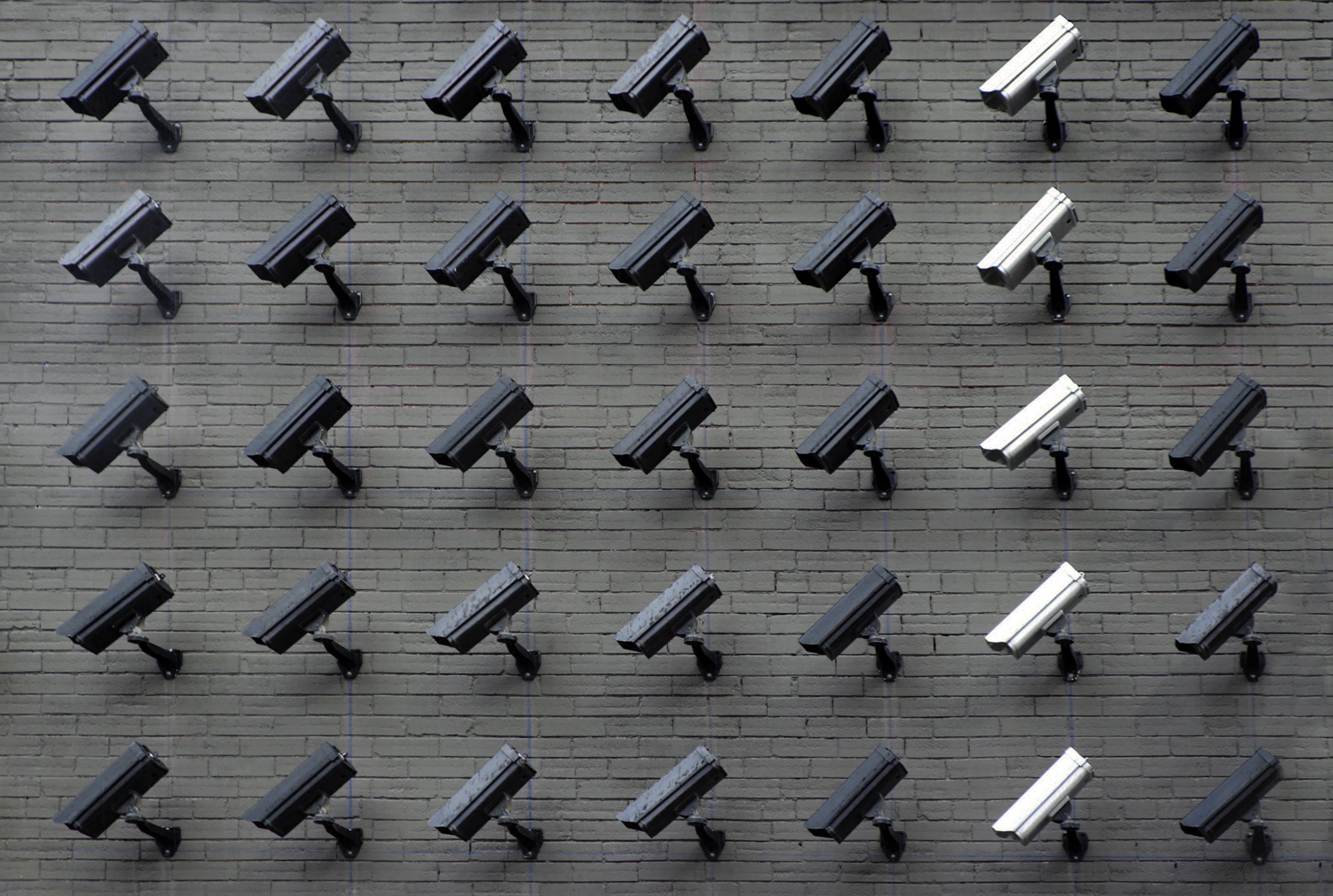 Many security cameras lined up on a wall